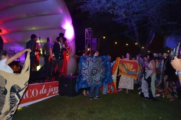 Público ergue cangas estampadas diante do palco-bolha do Buraco do Jazz: o Concurso de Cangas virou uma das marcas das edições no gramado da Praça dos Três Poderes, em Brasília.